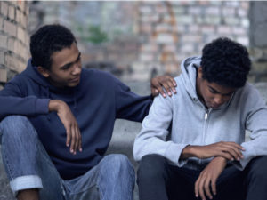 Afro-american teenager trying to make peace with friend, helping boy in need
